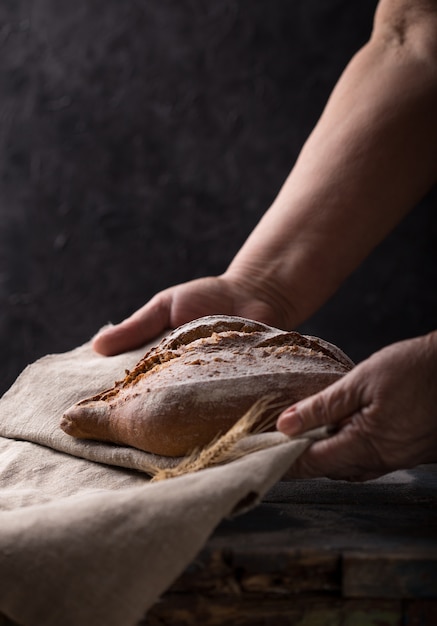 Chleb, kobieta ręce, trzymając świeżo zakwas chleb na rustykalnym tle. Poziomy z copyspace