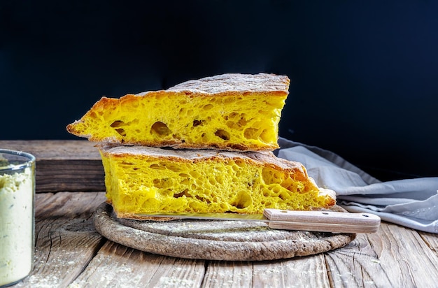Zdjęcie chleb kurkumowy na mące do serwetek i kurkuma w proszku na drewnianym stole z ciemnym tłem