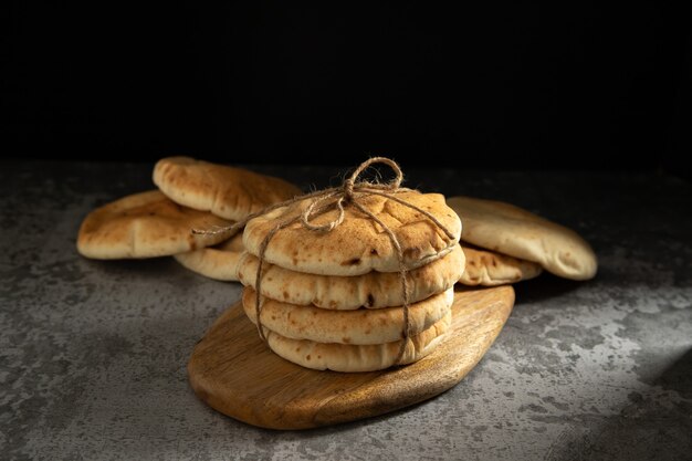 Chleb Pita, miękkie pieczone flatbreads, związane sznurkiem na rustykalnej drewnianej desce na ciemnym tle