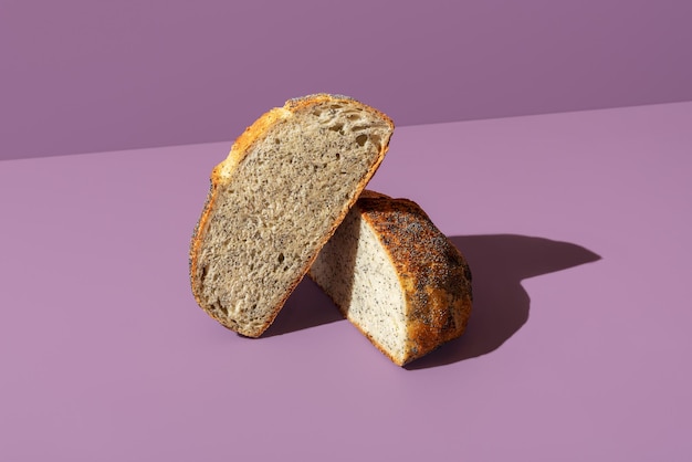 Chleb z makiem pokrojony na pół odizolowany na fioletowym tle