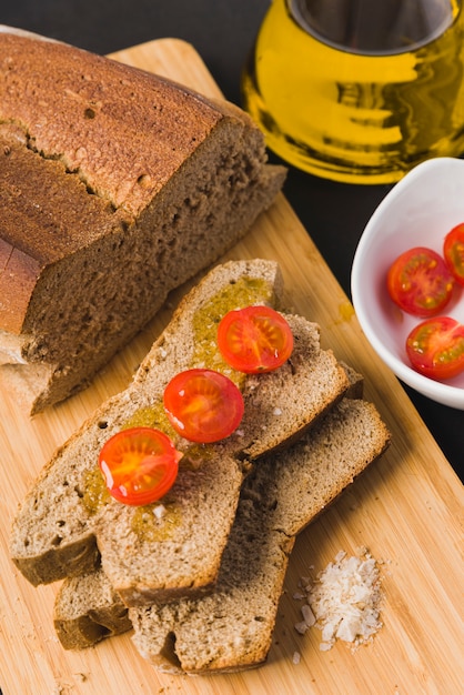 Chleb żytni, kromki chleba z pomidorkami cherry, oliwą i solą, pomidory cherry, olej i sól