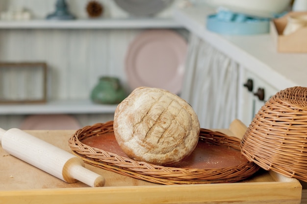 Chleby w pobliżu wiklinowego kosza na stole w rustykalnej kuchni. Kompozycja w kuchni w studio fotograficznym.
