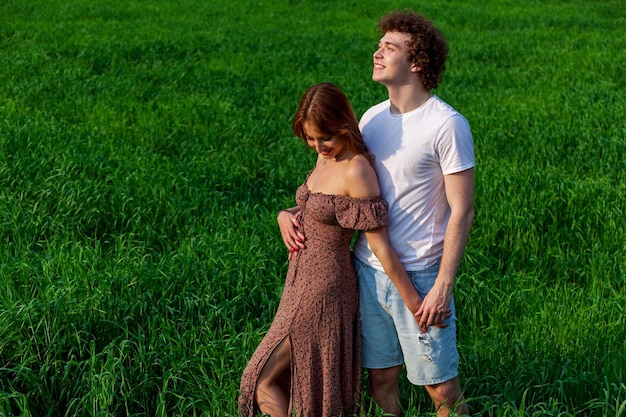 Zdjęcie chłopak i dziewczyna uściskają się na zielonym polu romantyczna sesja zdjęciowa zakochanej pary na zielonym polach pszenicy