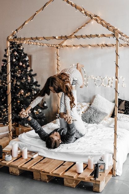 Zdjęcie chłopak trzyma w powietrzu swoją dziewczynę nad sobą. są w sennej pozie w uroczym świątecznym pokoju.