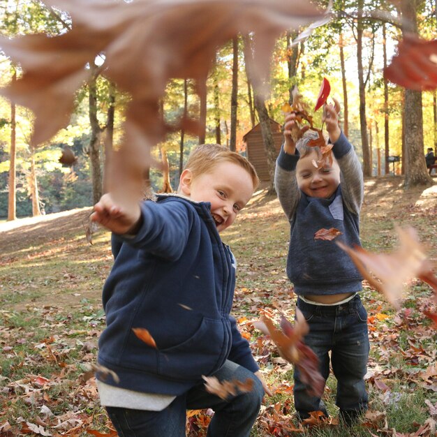 Chłopcy bawiący się jesiennymi liśćmi