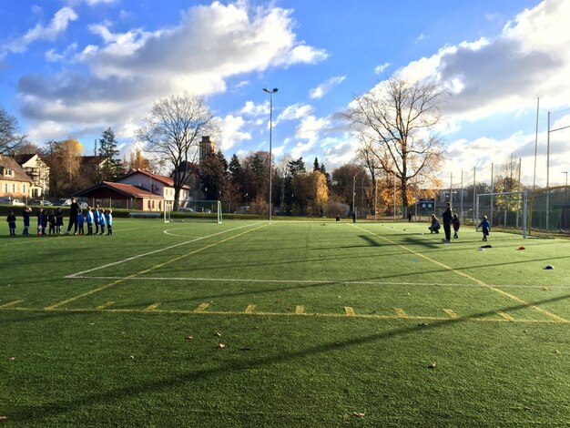Zdjęcie chłopcy grają w piłkę nożną na boisku przeciwko niebu