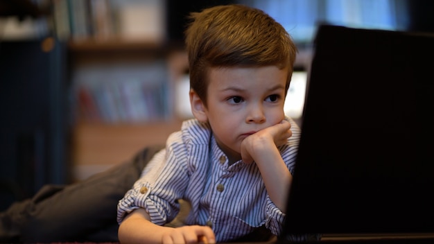 Chłopczyk W Niebieskiej Koszuli Oglądając Na Laptopie