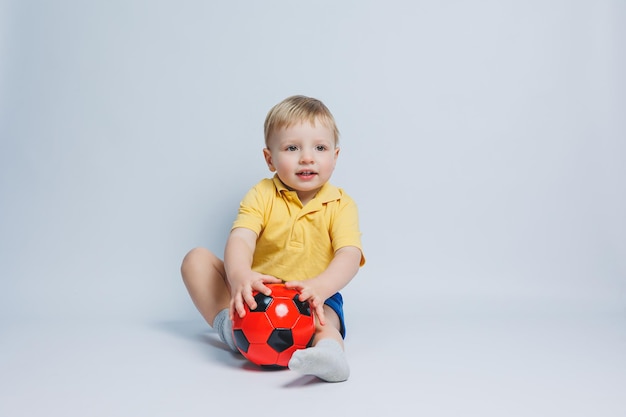 Chłopiec 34 lat kibic piłki nożnej w żółtej koszulce z piłką w dłoniach trzymający piłkę w dłoniach na białym tle na białym tle Pojęcie sportu rodzinnego rekreacji