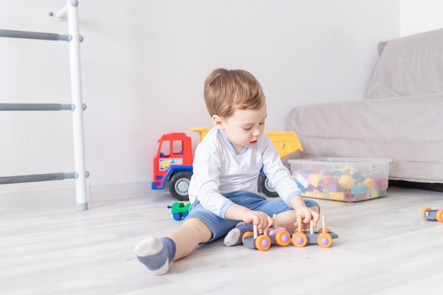 Chłopiec bawi się drewnianymi zabawkami w domu na podłodze