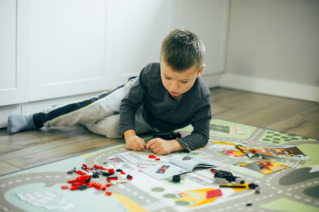 Chłopiec bawi się kostkami lego w pomieszczeniu krytym. Koncepcja stylu życia