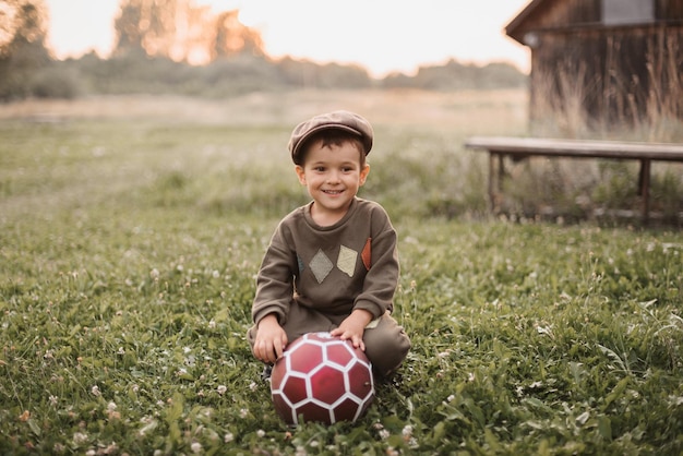 Chłopiec bawi się piłką nożną na świeżym powietrzu na wsi Szczery uśmiech chłopca Dzieciństwo na świeżym powietrzu
