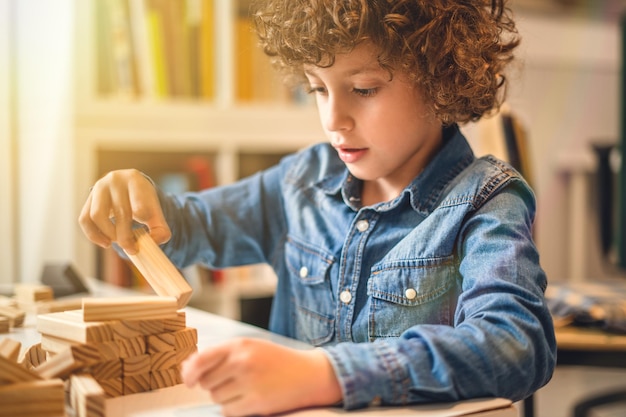 Zdjęcie chłopiec bawiący się drewnianymi blokami w domu