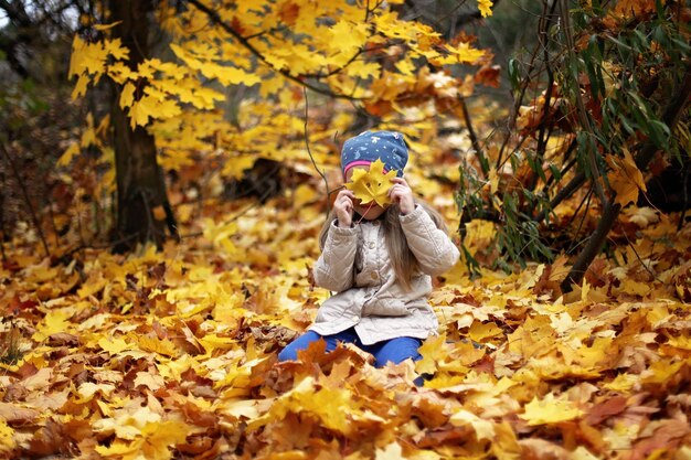 Chłopiec bawiący się jesiennymi liśćmi