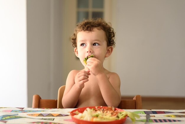 Chłopiec bez koszuli jedzący jedzenie w domu