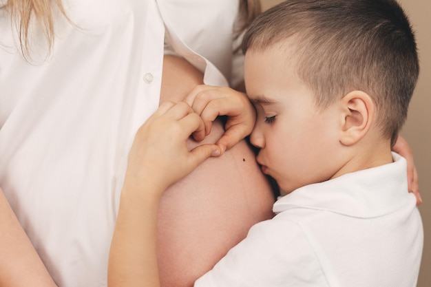 Zdjęcie chłopiec całuje ciężarny brzuch mamy