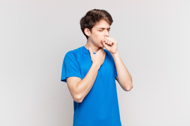 Chłopiec chory z bólem gardła i objawami grypy, kaszel z zakrytymi ustami