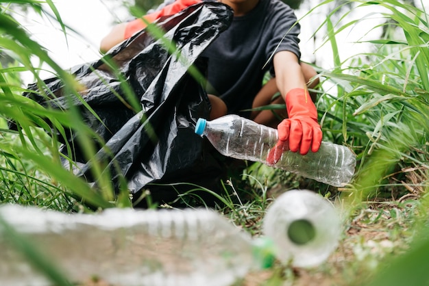 Chłopiec człowiek ręka podnieść plastikową butelkę w lesie. ochrona przyrody i koncepcja środowiska.