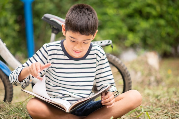 Chłopiec Czytelniczej Książki Obsiadanie Z Bicyklem W Parku