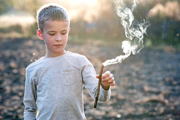 Chłopiec dziecko bawi się na zewnątrz palenia drewniany kij.