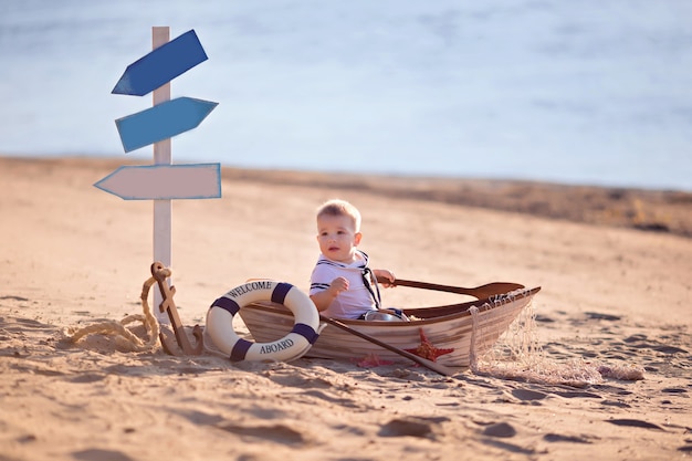 Chłopiec dziecko siedzi w łodzi na plaży