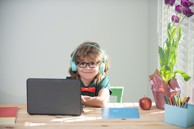 Chłopiec dziecko w słuchawkach za pomocą laptopa w domu nauczanie w domu na odległość online