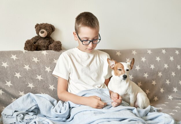 Chłopiec Dziecko Z Psem Jack Russell Terrier Siedzi Na Kanapie, Chłopiec Ma Przeziębienie