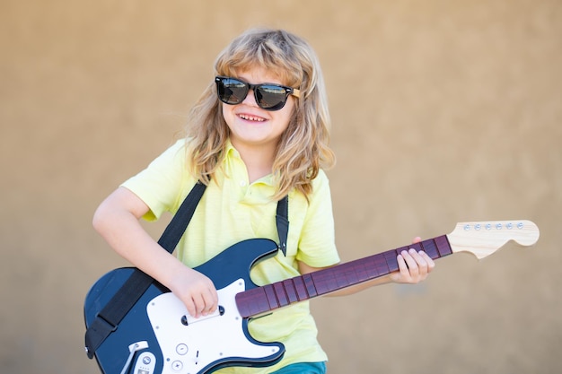 Chłopiec gitarzysta Śmieszne dziecko rocka z gitarą Mały chłopiec w okularach przeciwsłonecznych Koncepcja muzyki dla dzieci