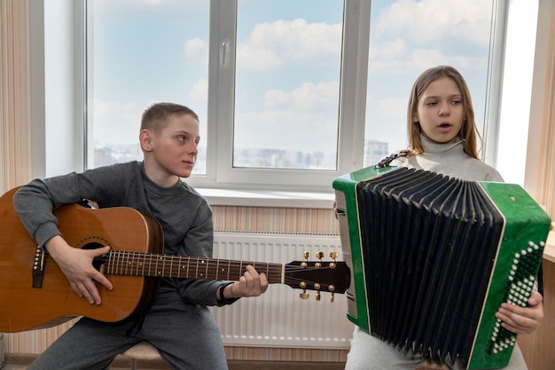 Zdjęcie chłopiec gra na gitarze, a dziewczyna razem z nim