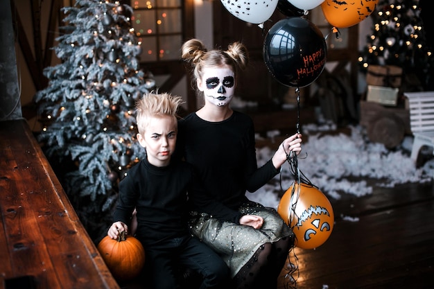 Chłopiec i dziewczynka w karnawałowych strojach przerażają Halloweenowe przyjęcie