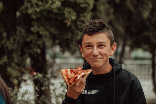 Chłopiec je pizzę podczas przerwy na lunch w szkole Selektywna ostrość Zdjęcie wysokiej jakości