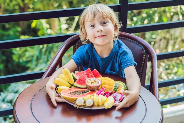 Chłopiec je różne owoce na tarasie.