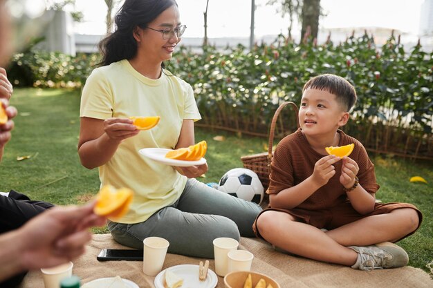 Chłopiec jedzący pomarańcze na pikniku