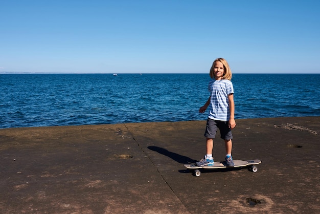 Chłopiec jedzie na longboardzie na molo w słoneczny dzień