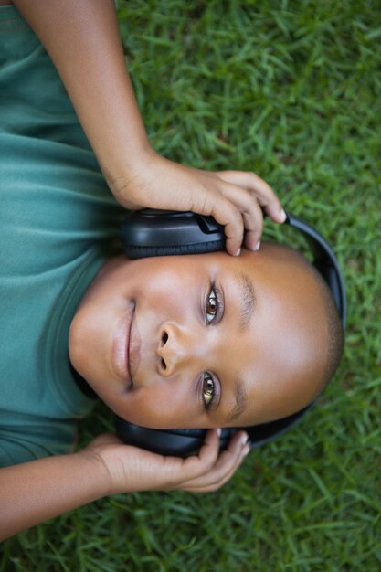 Chłopiec lying on the beach na trawie słucha muzyczny ono uśmiecha się przy kamerą
