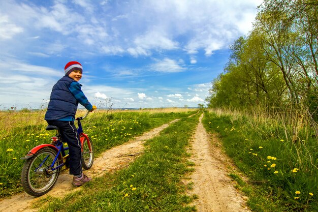 Chłopiec na rowerze na wiejskiej drodze wiosny pogodnym dniu