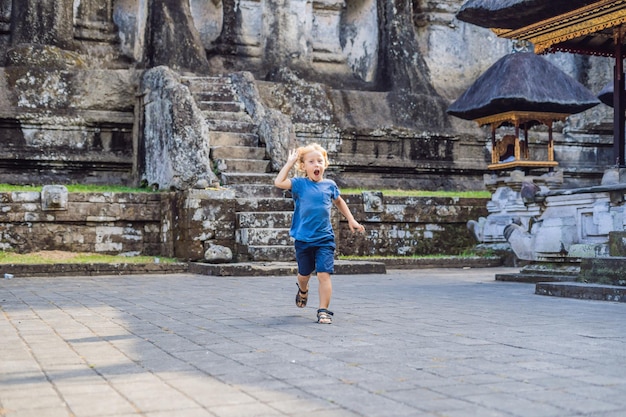 Chłopiec na tle Gunung Kawi. Starożytna wyrzeźbiona w kamieniu świątynia z królewskimi grobowcami. Bali, Indonezja. Podróżowanie z dziećmi koncepcja ..