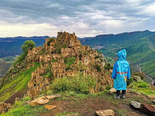 Chłopiec na tle wioski Gamsutl w górach Kaukazu na szczycie klifu Dagestan Rosja czerwiec 2021