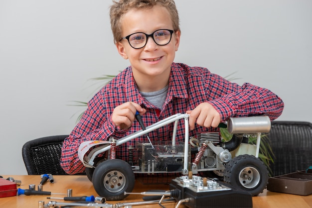 Zdjęcie chłopiec naprawia wzorcowego radiowego samochód w domu