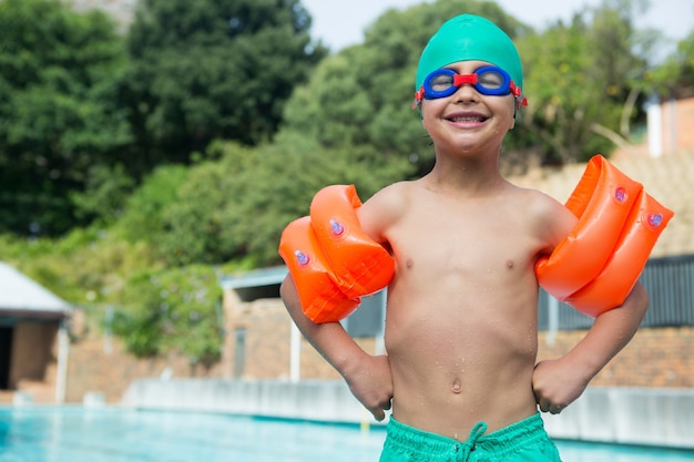 Chłopiec noszenie opasek na ramię, stojący przy basenie