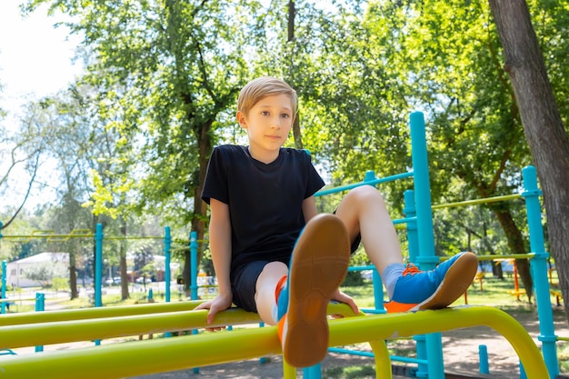 Chłopiec odpoczywa siedzący na drążkach gimnastycznych w parku