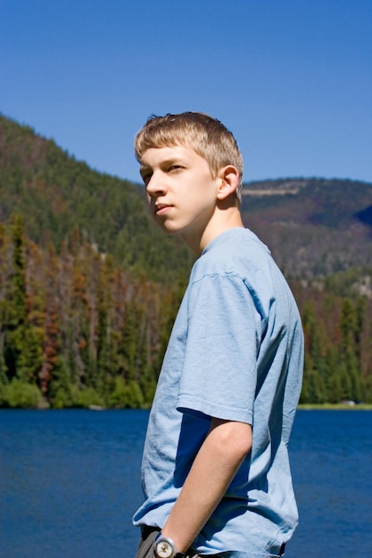 Zdjęcie chłopiec patrzący w stronę jeziora w lesie