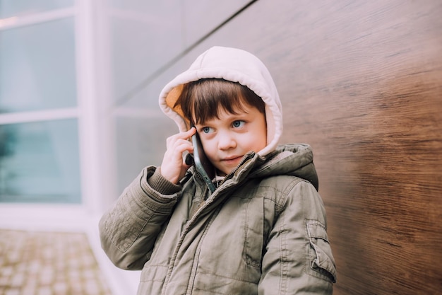 Chłopiec patrzy na swój telefon w mieście stylu życia Nowoczesne technologie Nowoczesne dzieci Dziecko i telefon