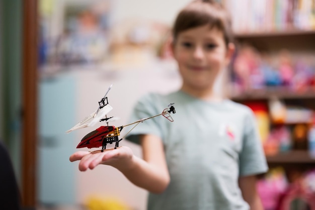 Chłopiec pokazuje zabawkowy helikopter na pilocie w pokoju dziecięcym