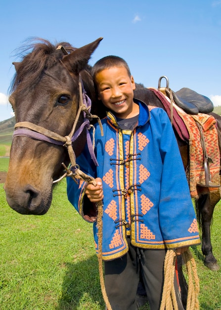 Chłopiec przechyla jego głowę jego koń i ono uśmiecha się przy outdoors.