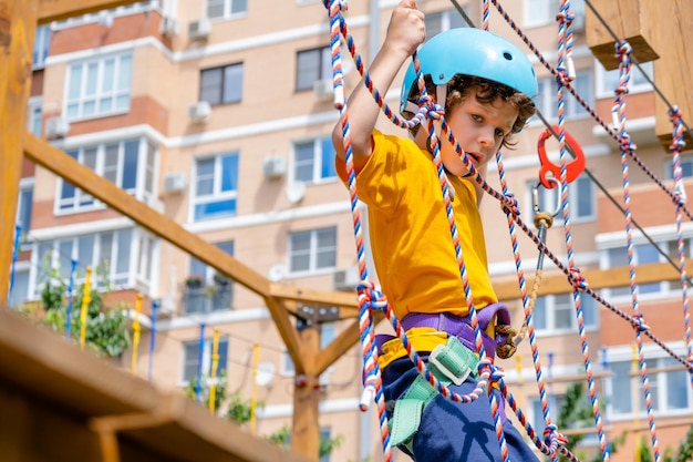 Zdjęcie chłopiec przekraczający kurs wysoki element lin w parku przygód koncepcja plenerowa wspinaczka sport ekstremalny phys