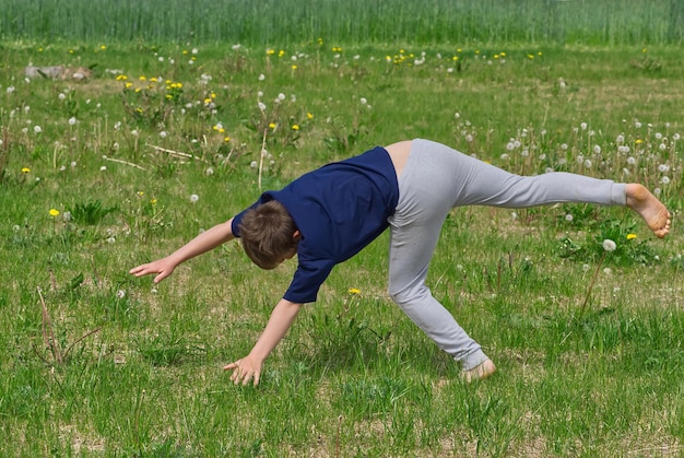 Chłopiec robi koło akrobatyczne na trawie