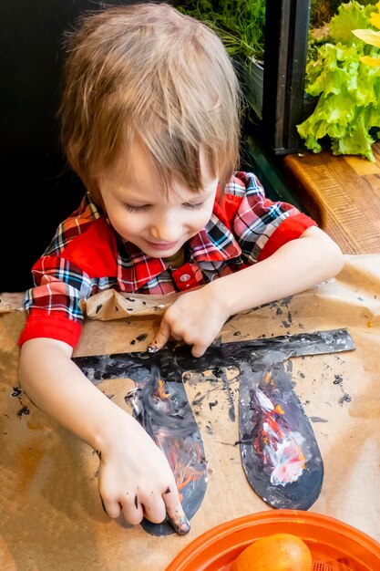 Chłopiec rysuje uszy ręcznie robionego króliczka wielkanocnego wykonanego z tektury Przygotowanie do obchodów świąt wielkanocnych