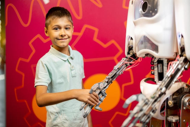 Zdjęcie chłopiec ściska rękę humanoidalnemu robotowi w muzeum