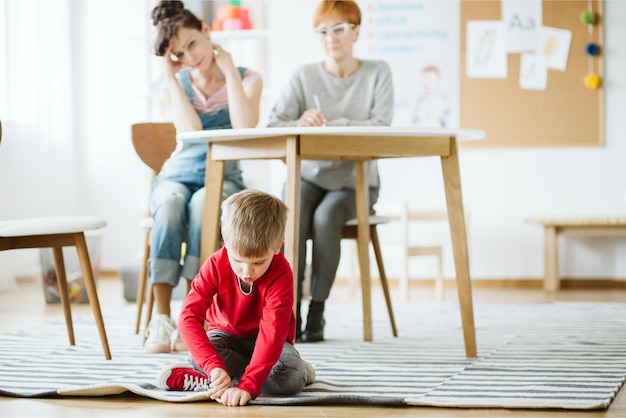 Chłopiec siedzi na podłodze w klasie z napisem „żadnego dziecka nie ma na podłodze”