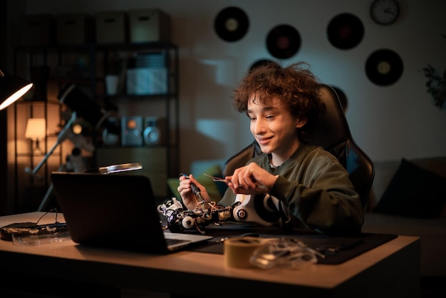 Chłopiec Siedzi Przy Biurku W Pokoju Wieczorem Kończy Lutowanie Robota, Który Jest Szkolnym Projektem
